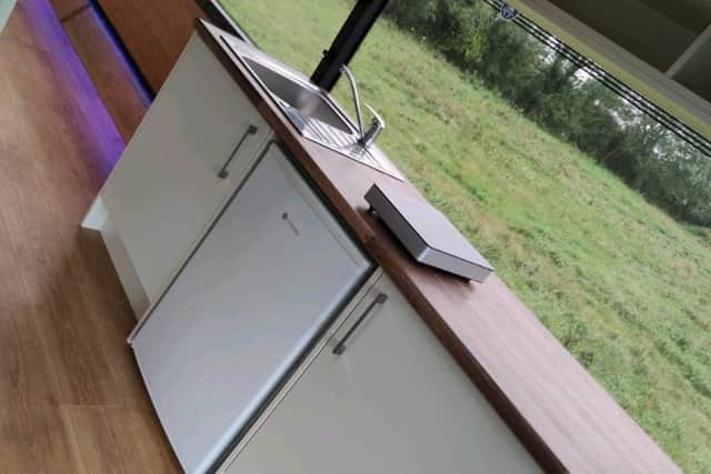 The bus is equipped with a modern kitchen including a full size fridge, sink and electric hob, and there's a breakfast bar with seating for two.