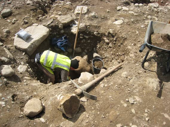 An archaeologist excavating a pit